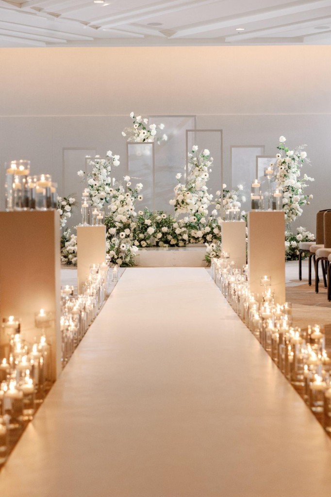 Elegant wedding ceremony aisle with candlelit floral arrangements